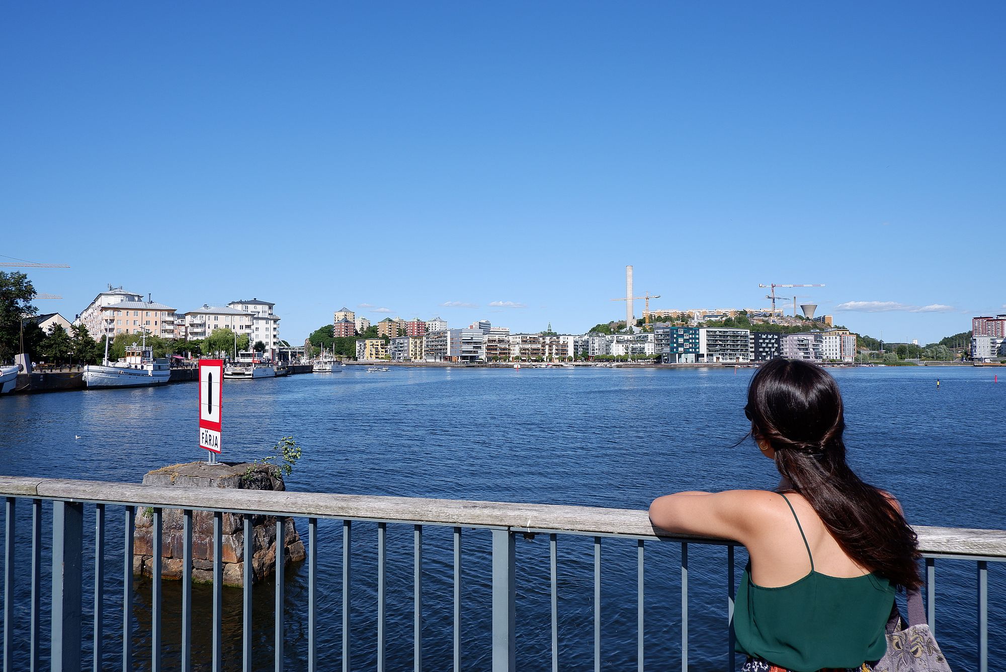 Marina appuyée contre une rambarde au bord de l'eau à Stockholm.
