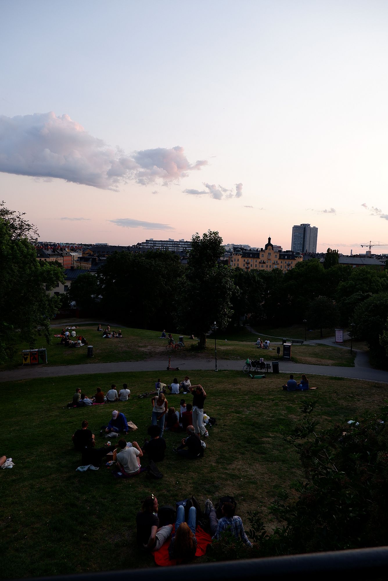des groupes de personnes assises ou allongées dans l'herbe, le soir à Stockholm.