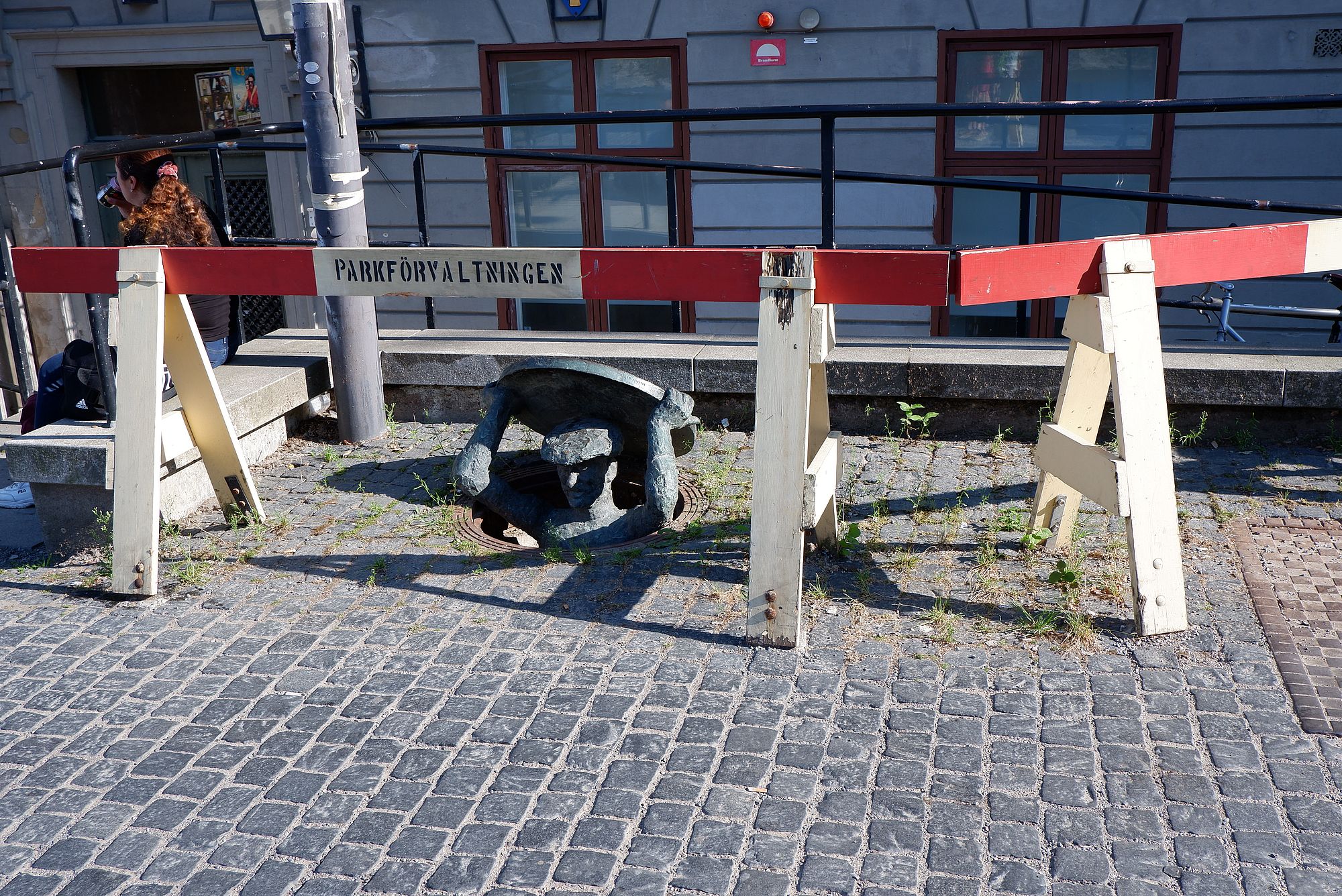 Une sculpture d'un homme sortant la tête d'une bouche d'égout