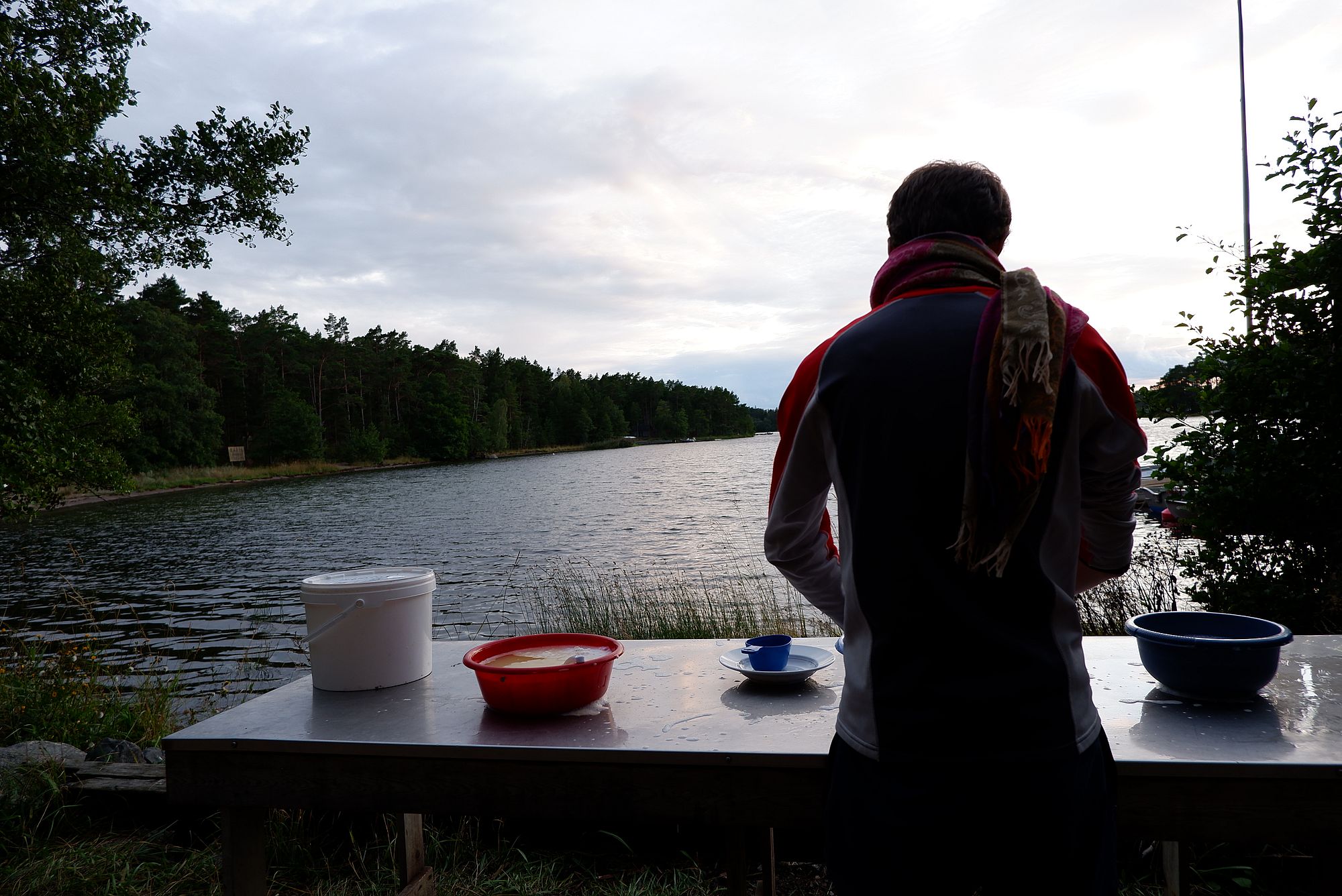 Ryan fait la vaisselle dehors face à l'eau.