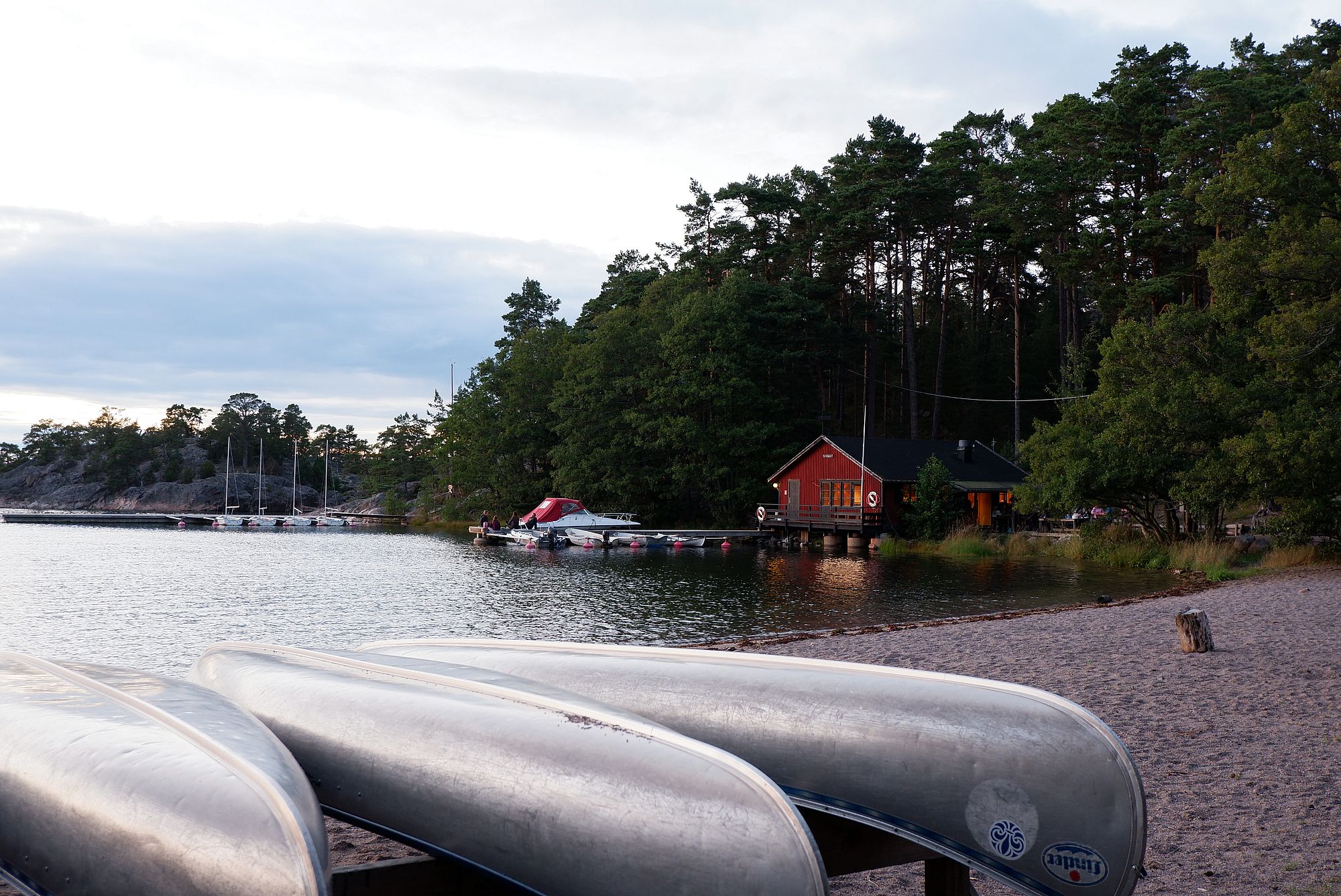 Vue sur la cuisine et cafétéria depuis la plage. Une maison en bois rouge au bord de l'eau.