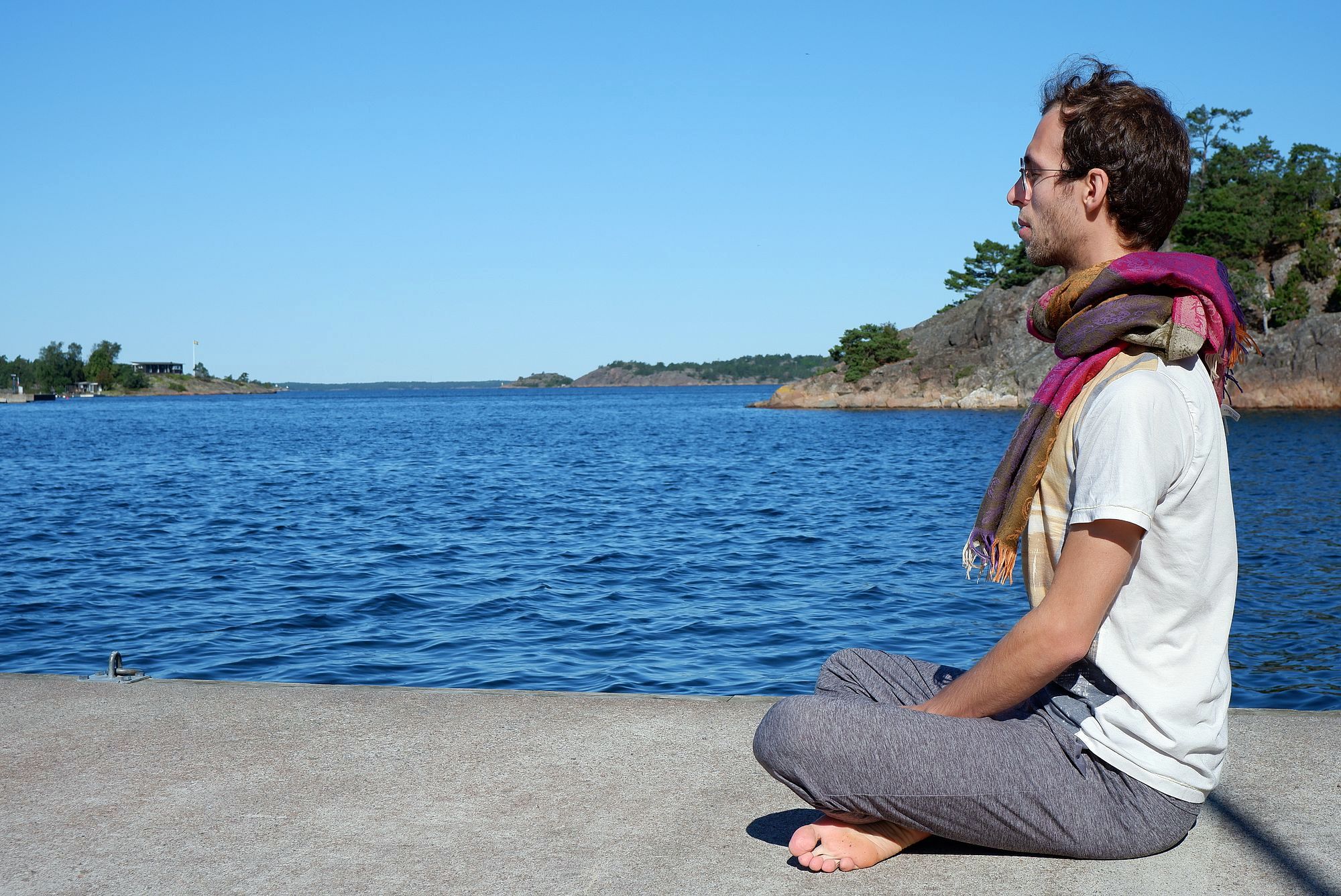 Ryan médite sur un ponton au bord de l'eau, sous le soleil