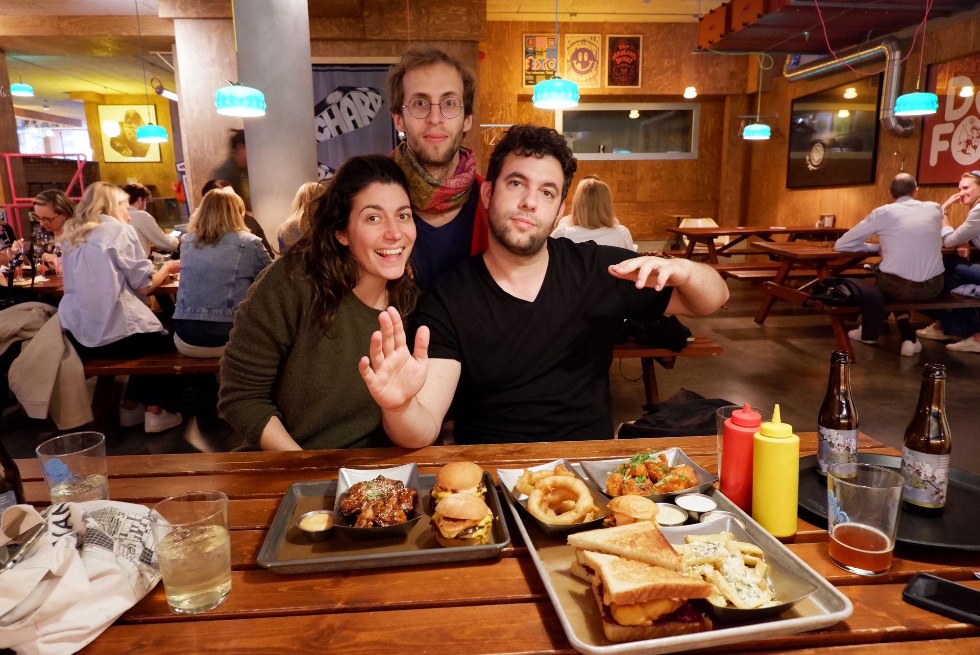Sarah, Ryan et Elie à Lådan, posant devant une table recouverte de burgers et autres aliments frits